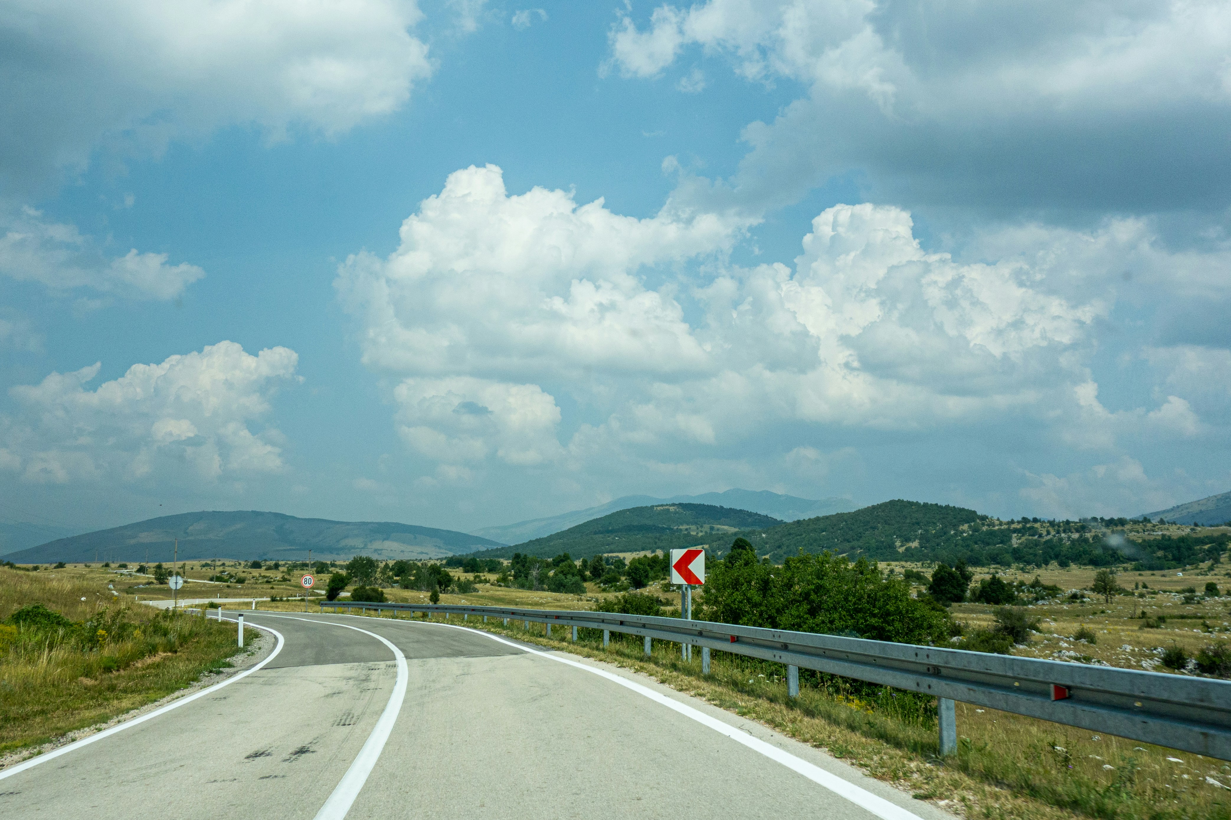 gray concrete road under blue sky and white clouds during daytime