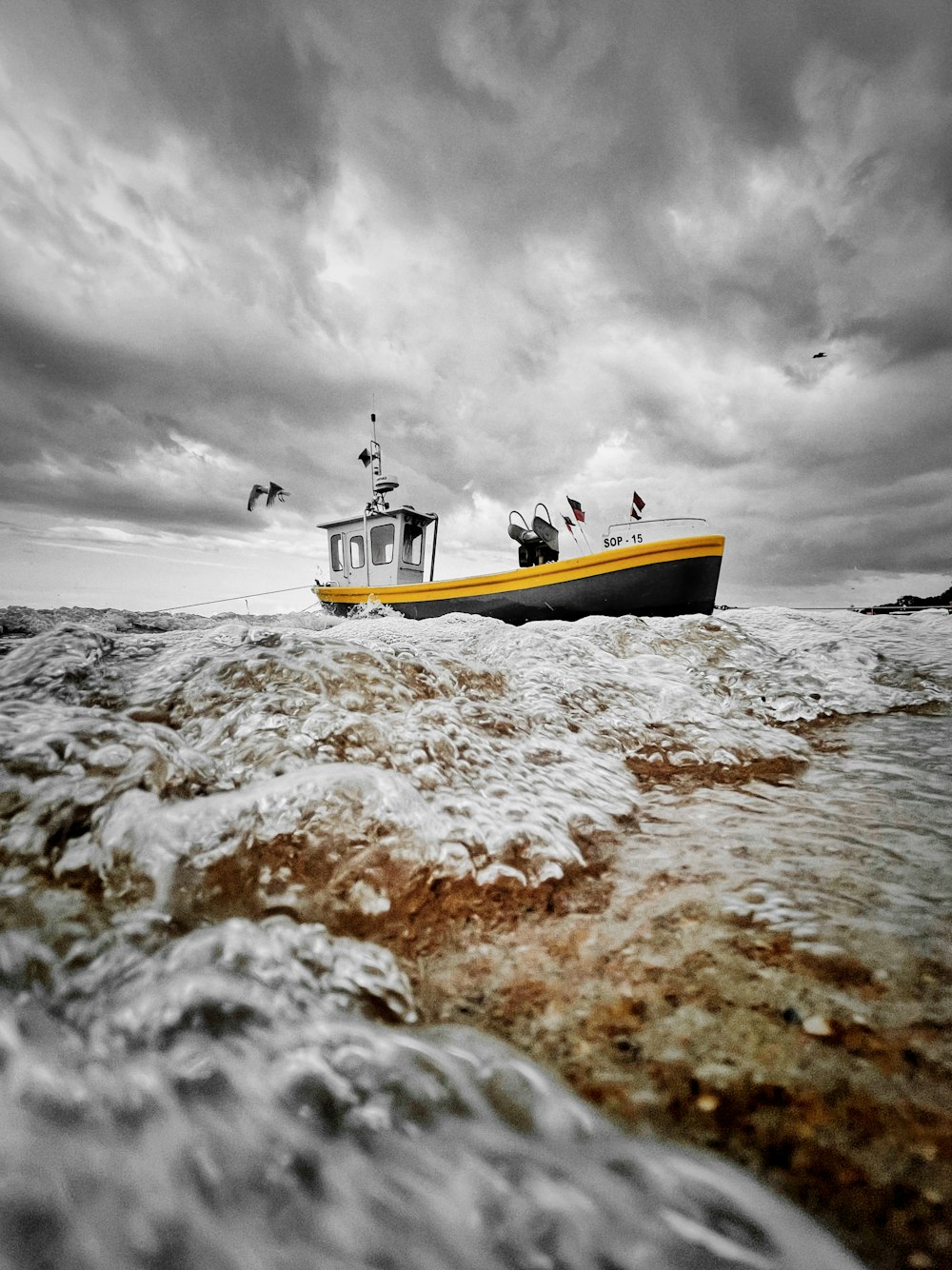 曇り空の下、海岸に浮かぶ黄色と白のボート