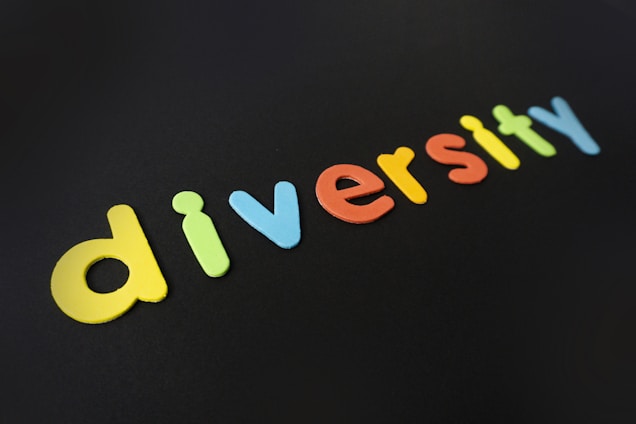Colorful letters spell out the word 'diversity' against a dark background. Each letter is a different vivid color, creating a striking contrast.