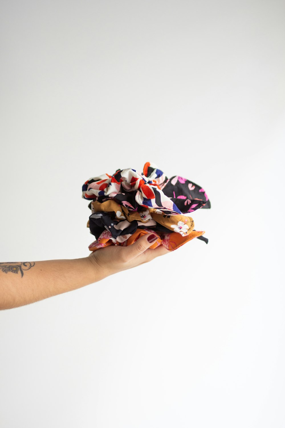 person holding white red and black floral textile