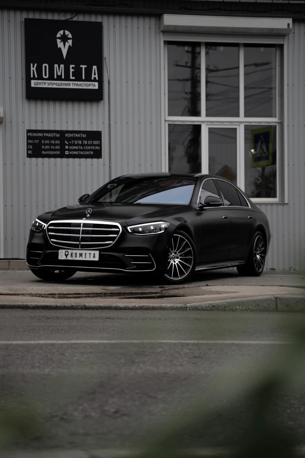 Black Mercedes-Benz sedan parked by a white building