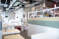 A bright café interior after complete renovation, showcasing fresh plaster and modern lighting.