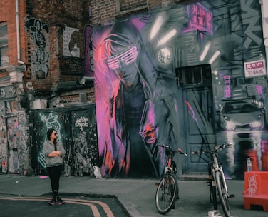 A street artist performing in front of a vibrant graffiti wall.