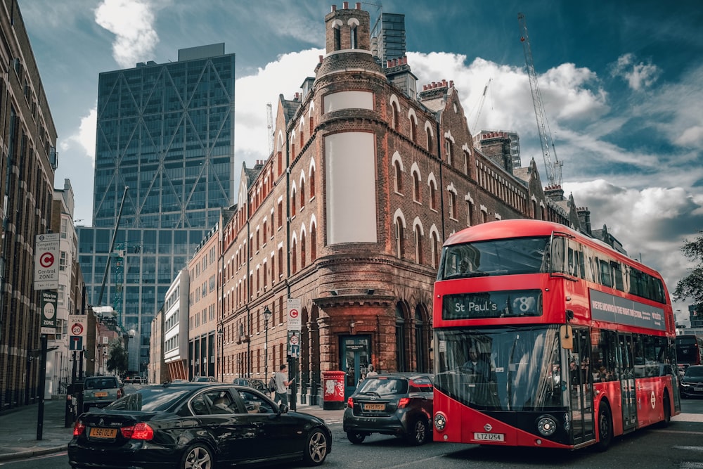 red double decker bus on road near brown concrete building during daytime