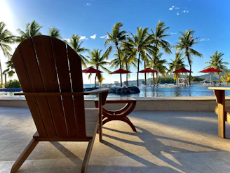 A sleek outdoor chaise lounge positioned by a pool with a bright blue sky overhead.