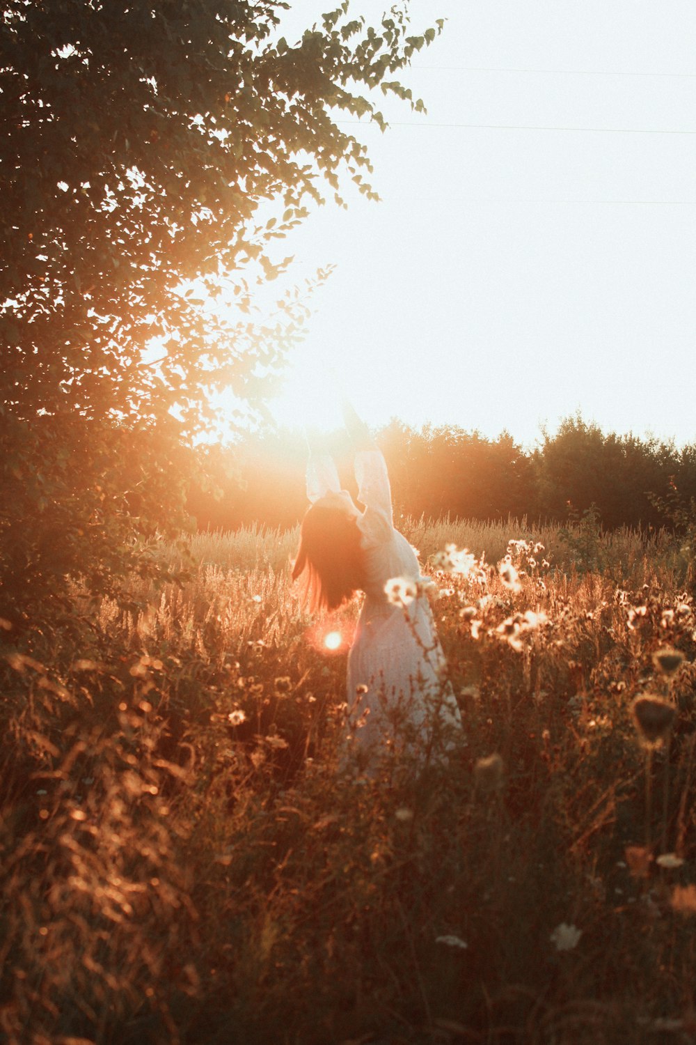 woman in white dress standing on brown grass field during sunset