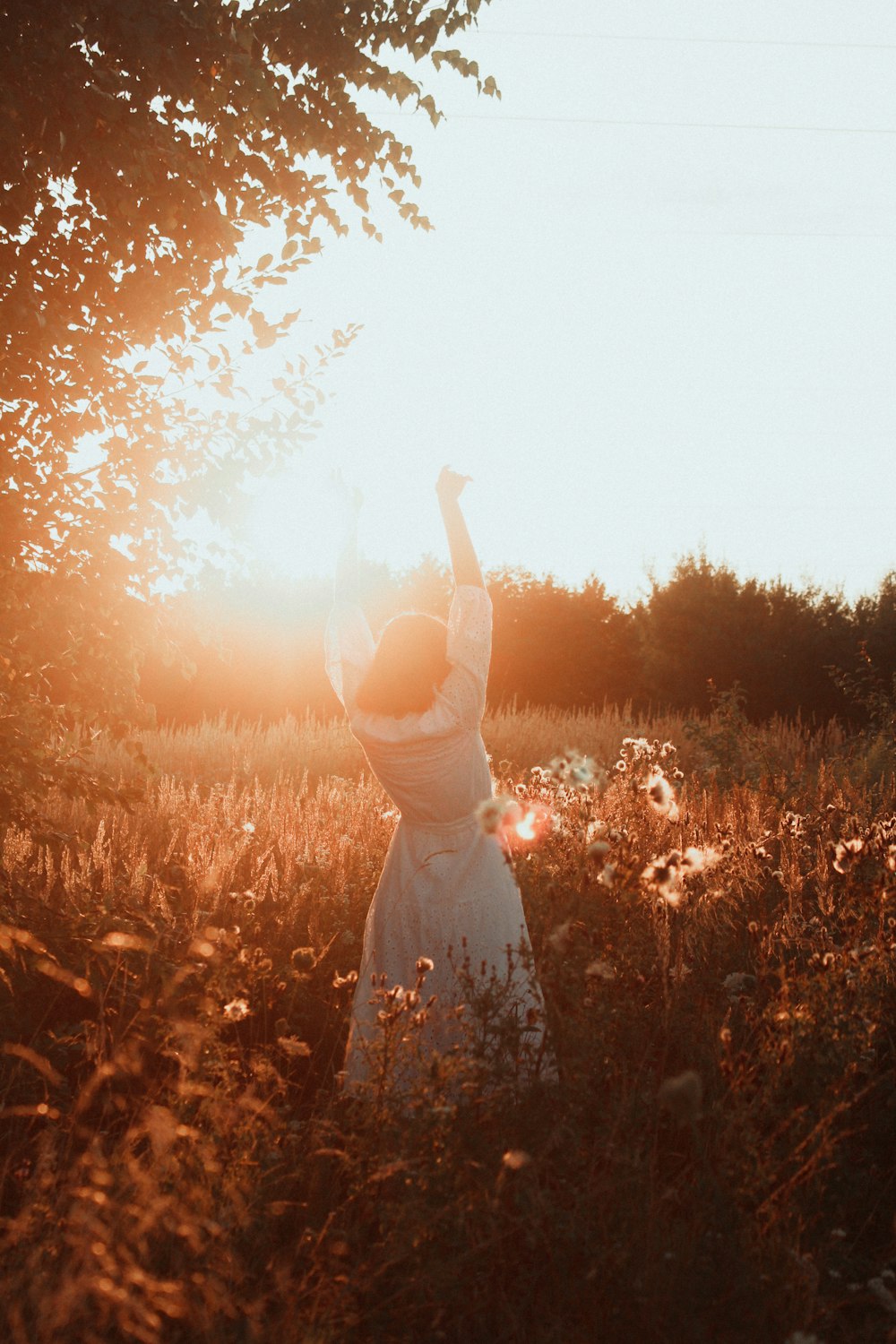 woman in white dress standing on brown grass field during sunset