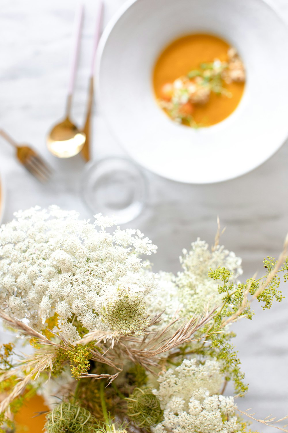 white flowers on white ceramic plate beside silver fork and bread knife