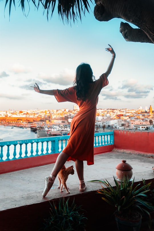 woman in orange dress standing on red concrete floor during daytime in Rabat Morocco