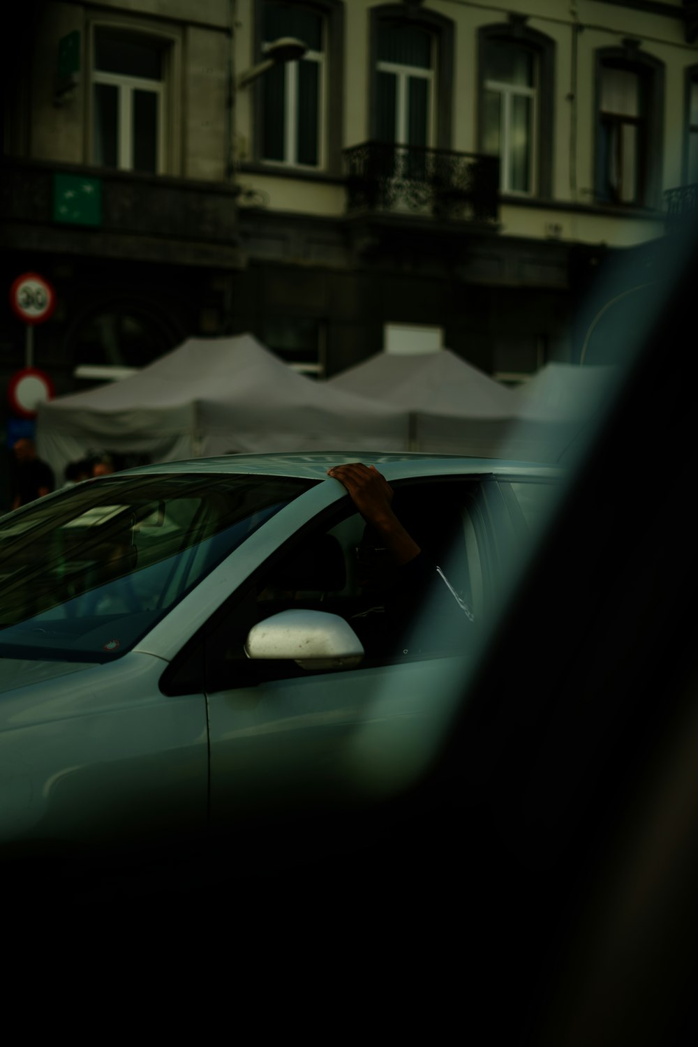 person in white dress shirt and brown pants standing in front of white car during daytime