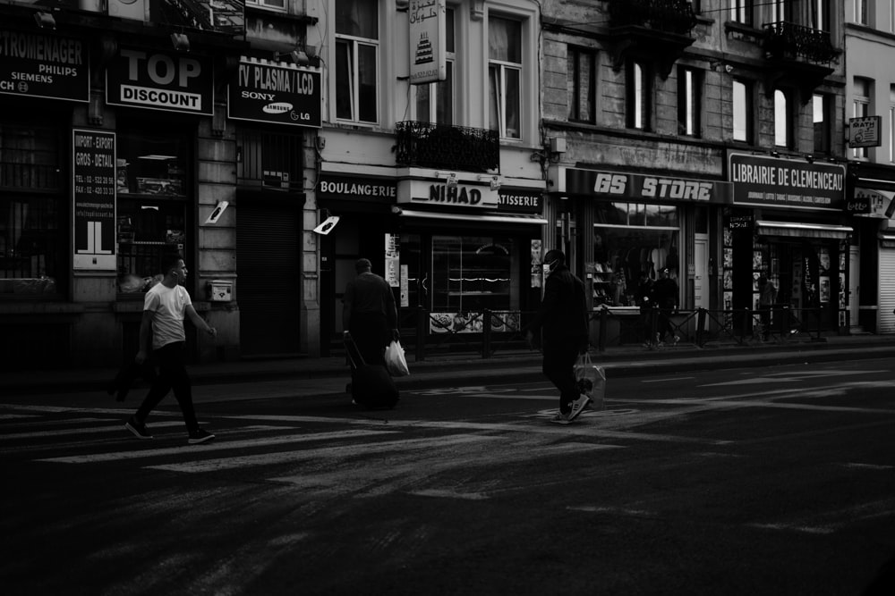 grayscale photo of people walking on sidewalk