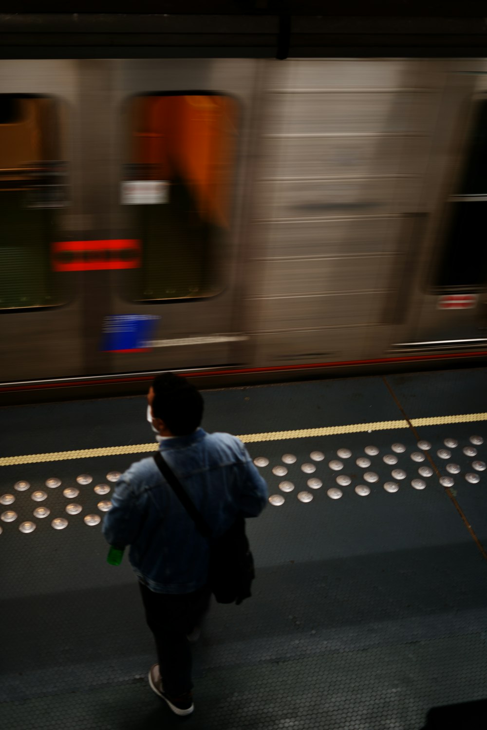 man in blue jacket standing on train station