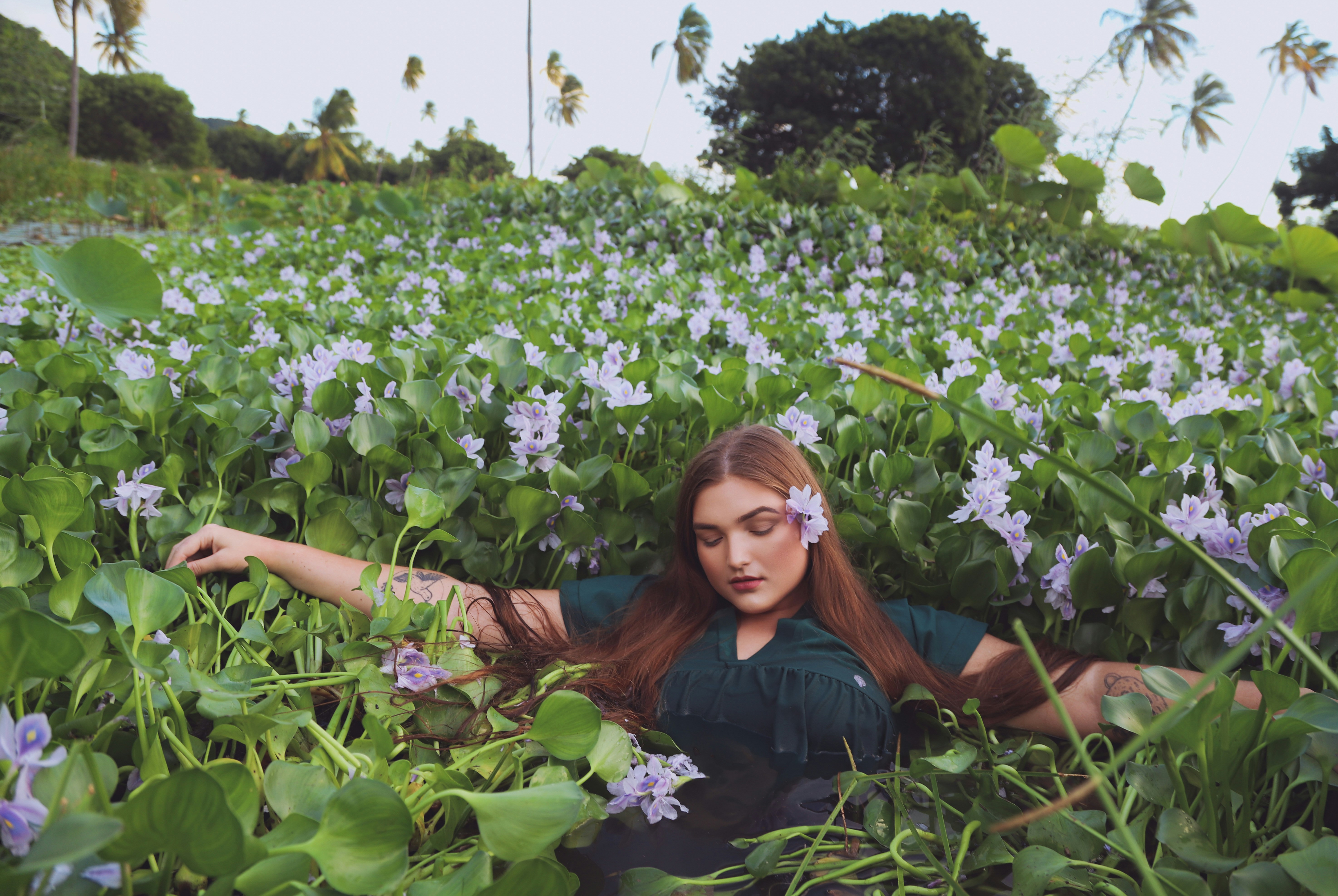 woman in black shirt sitting on green plants during daytime
