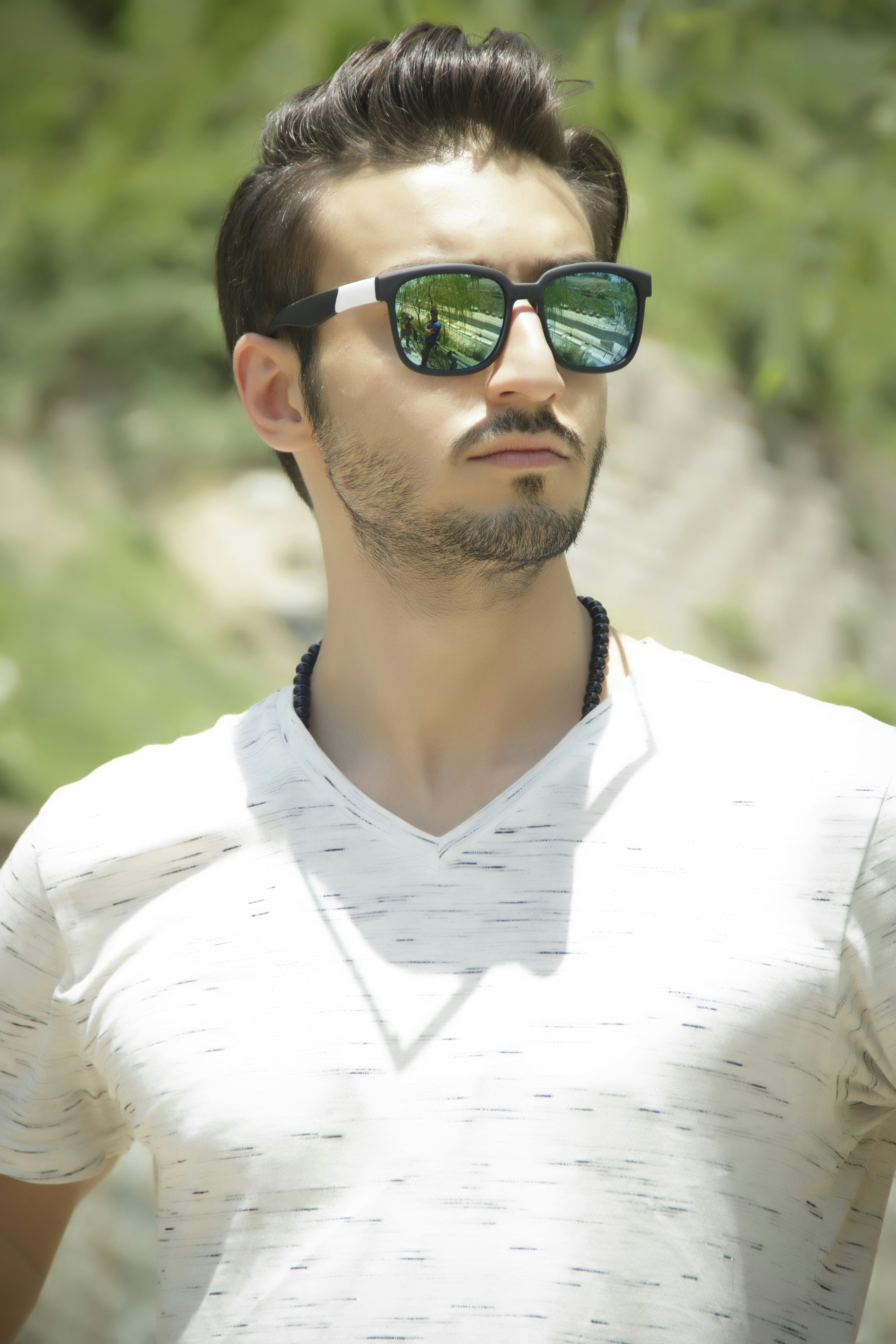 man in white v neck shirt wearing black sunglasses