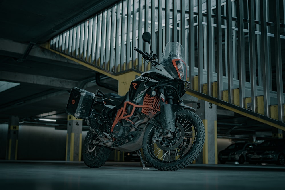 black and red sports bike parked beside white metal fence