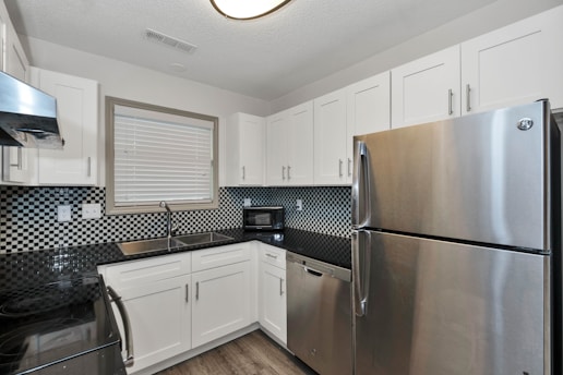 silver top mount refrigerator beside white wooden kitchen cabinet