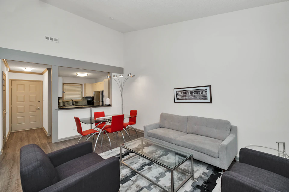Modern living room features glass coffee table and gray sofa facing large window