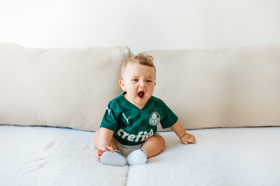 boy in green crew neck t-shirt sitting on white bed