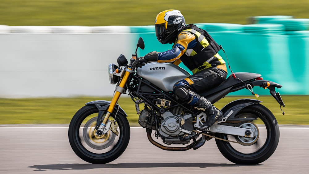 man in black and white motorcycle suit riding on white and orange sports bike