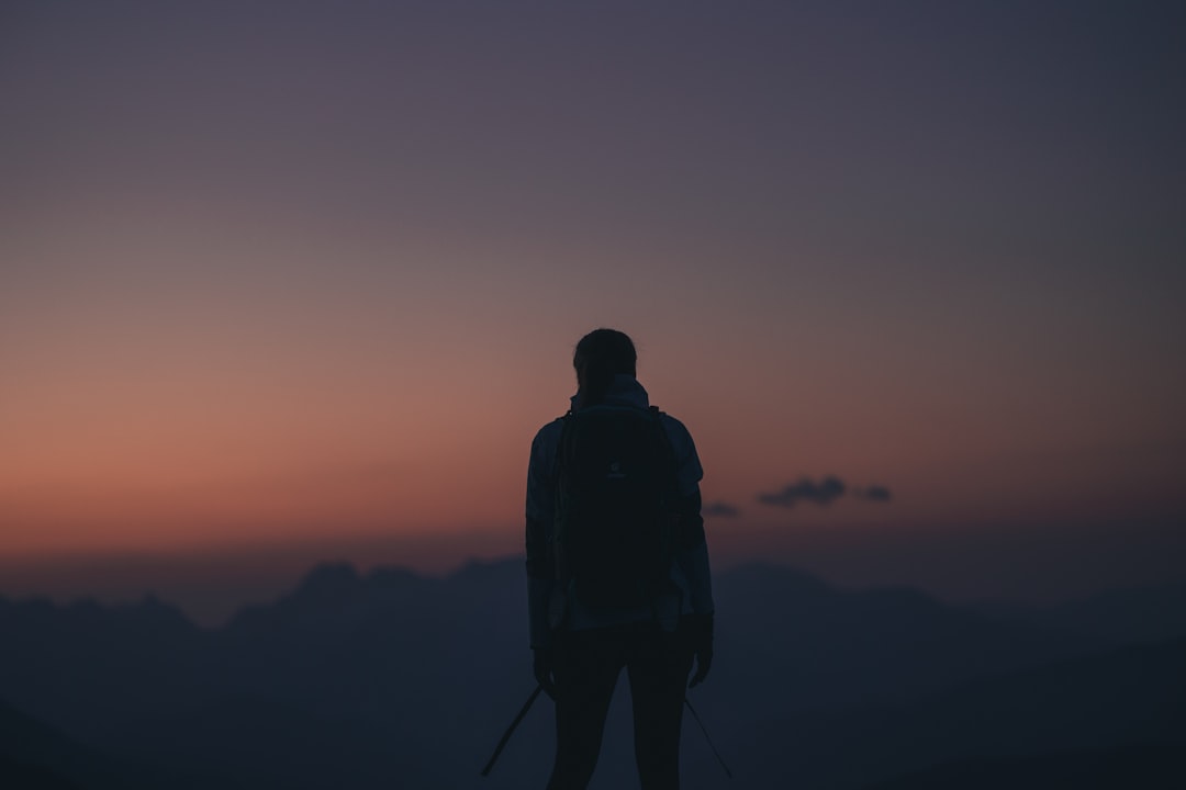 silhouette of man standing on hill during sunset