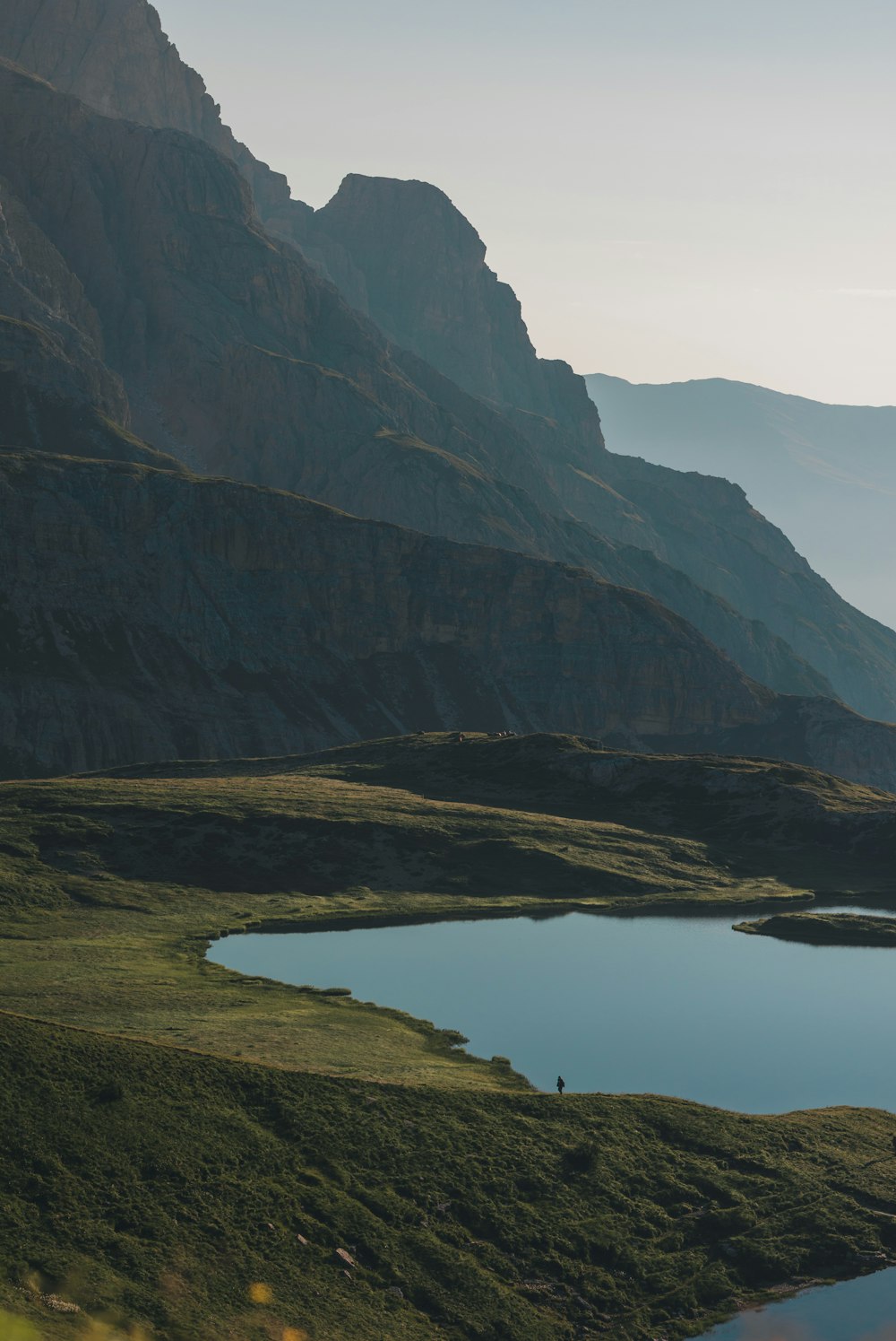 green and brown mountains beside lake during daytime