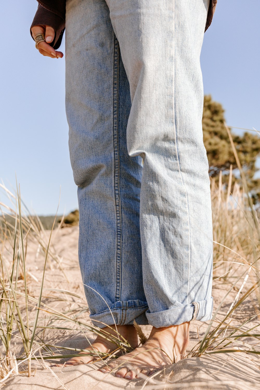 pessoa em jeans azuis em pé no campo de grama marrom durante o dia