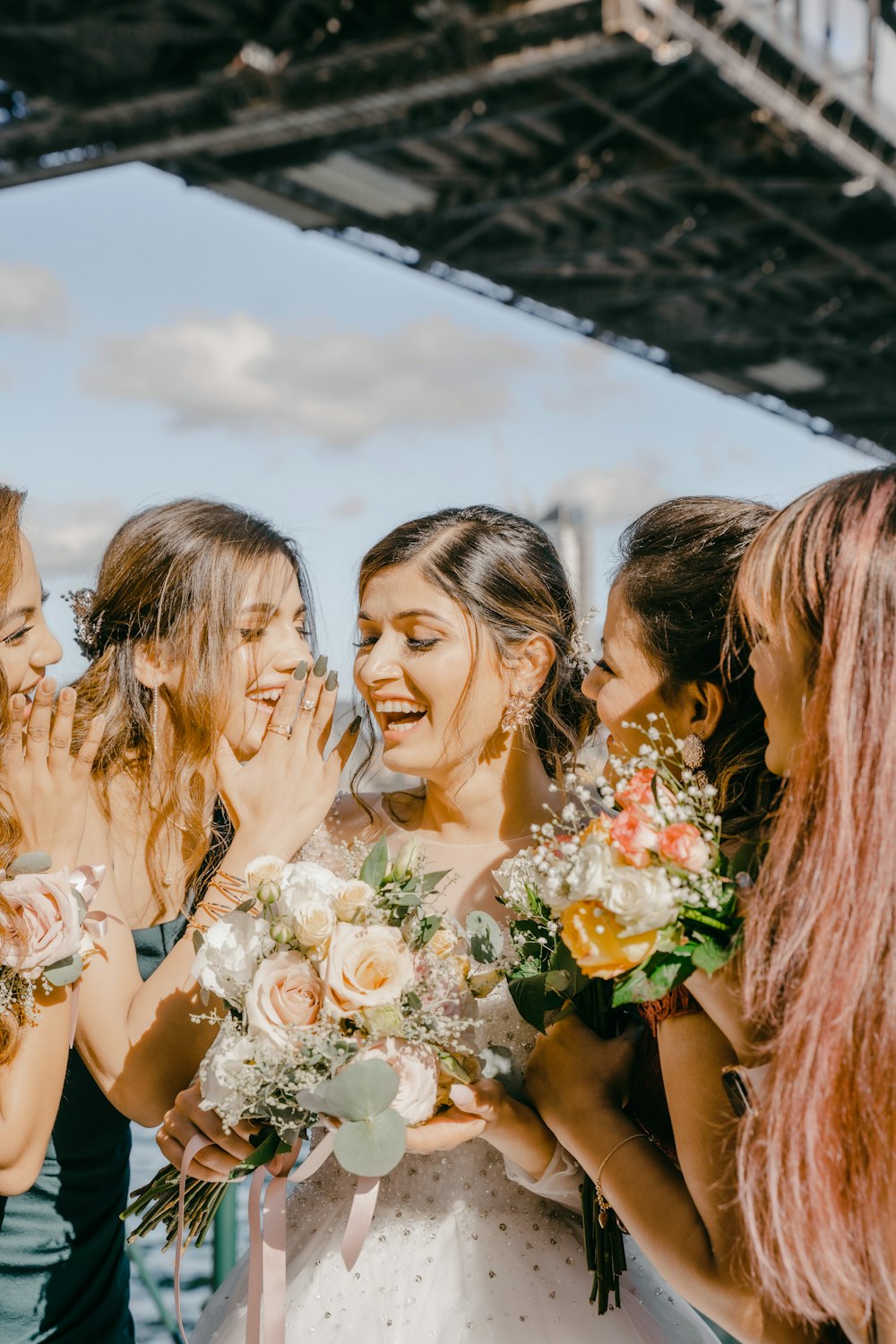 3 women in white floral dress holding bouquet of flowers