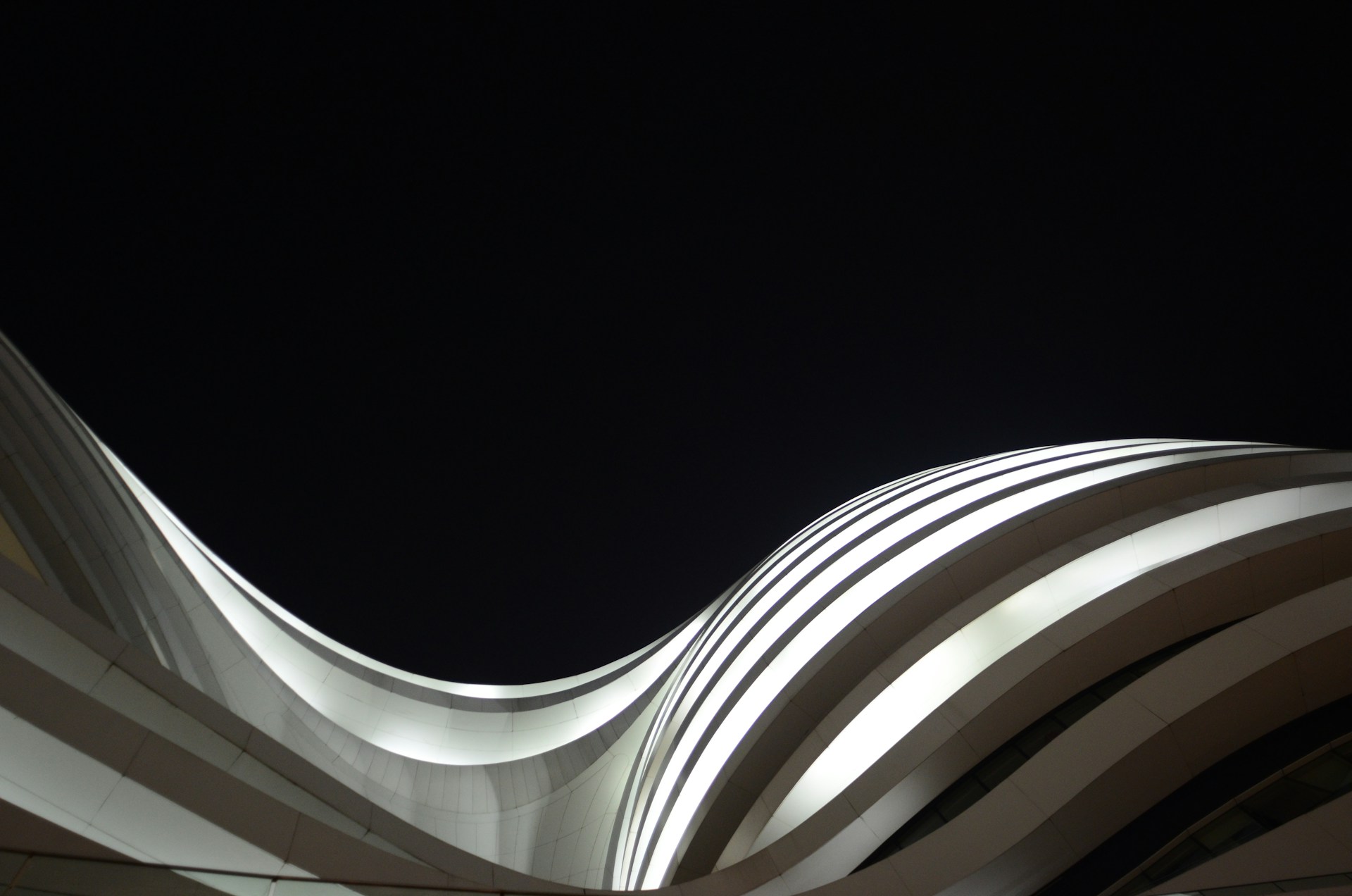 A visionary architectural concept blending organic curves and sharp angles, illuminated softly against a dark sky.