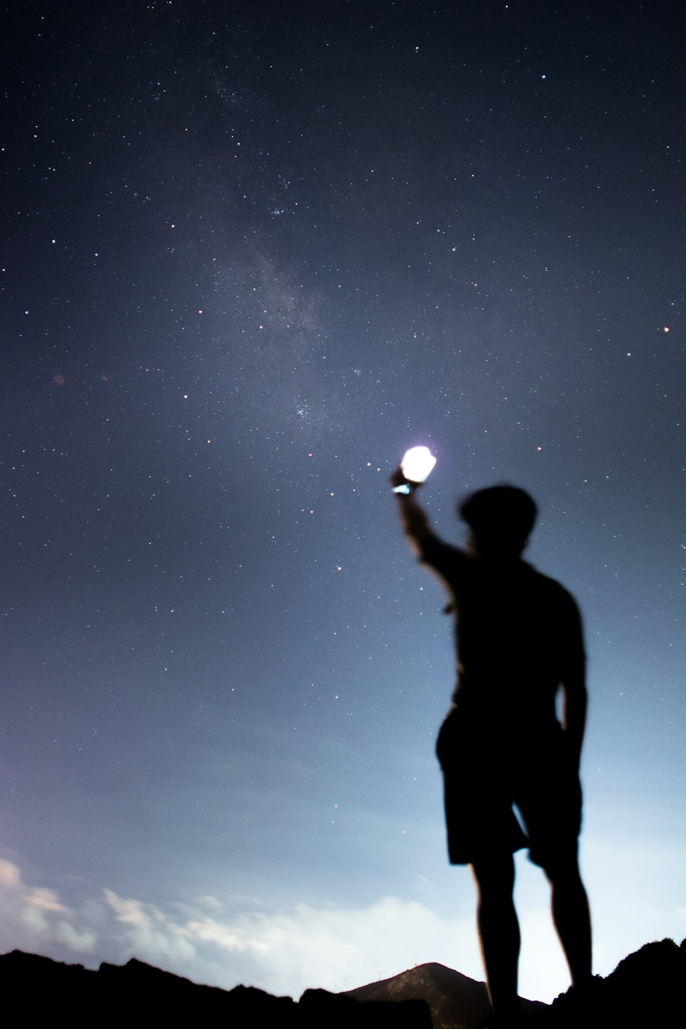 silhouette of man holding lighted light during night time