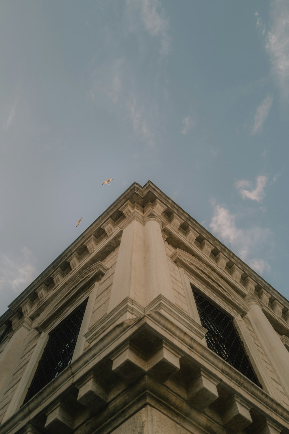Fotografía de ángulo bajo de un edificio de hormigón beige bajo el cielo azul durante el día