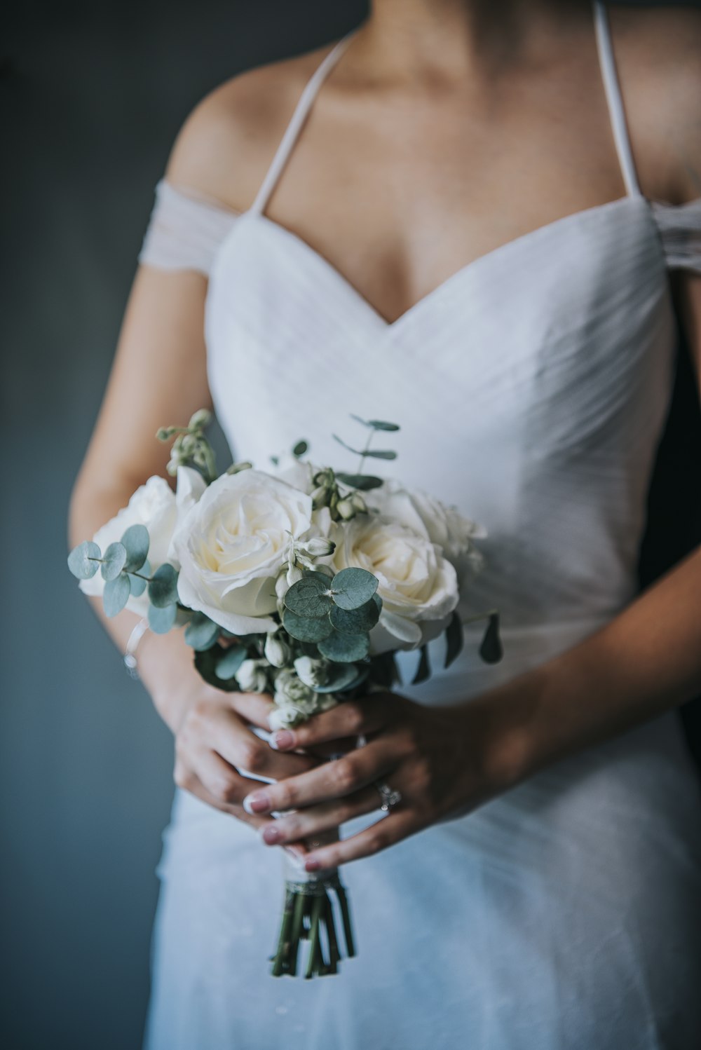 Frau in weißem ärmellosem Kleid mit weißem Rosenstrauß