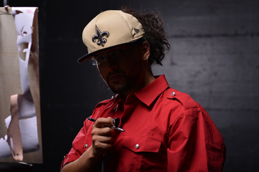 man in red dress shirt wearing white and black cap