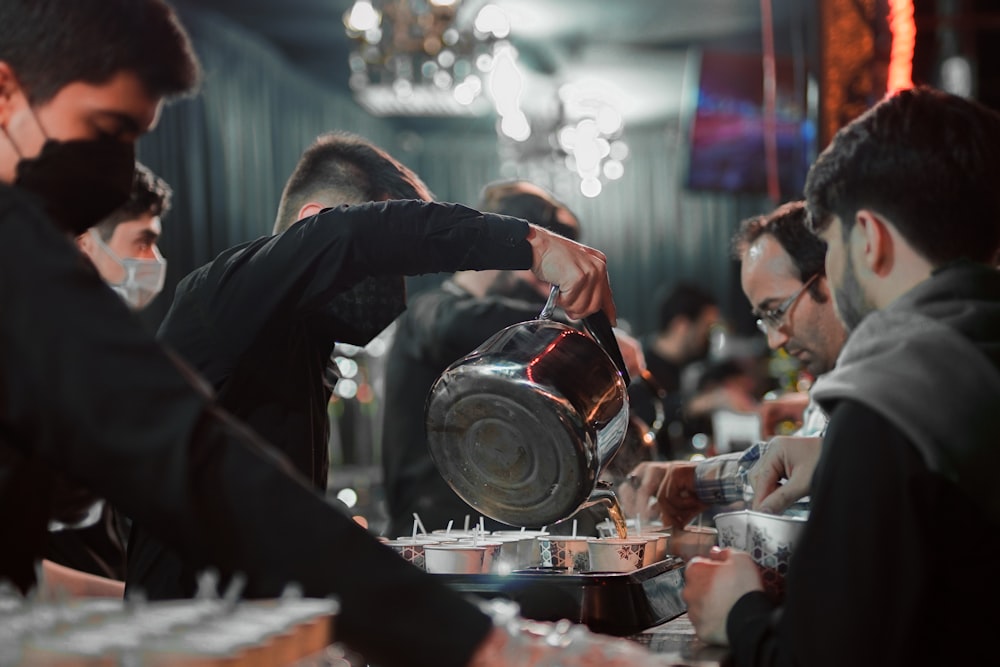 man in black long sleeve shirt pouring water on clear drinking glass