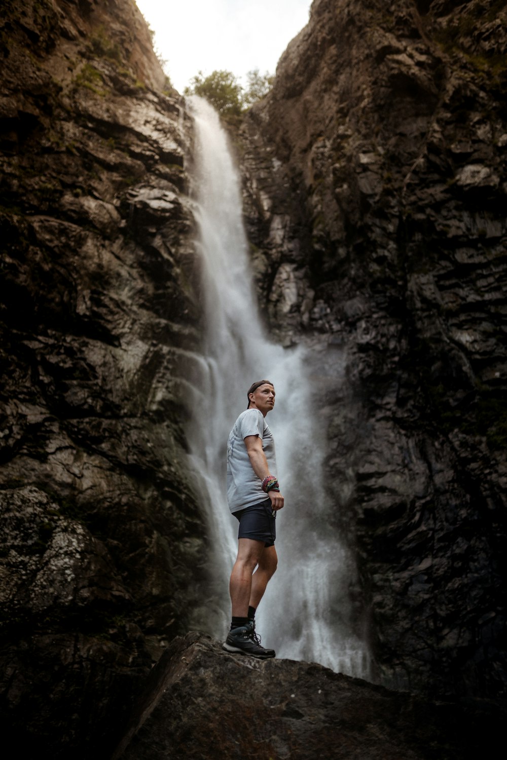 woman in white long sleeve shirt and black shorts standing on rock formation