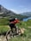 A cyclist riding on a scenic mountain trail surrounded by lush greenery.