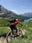 A cyclist riding on a scenic mountain trail surrounded by lush greenery.