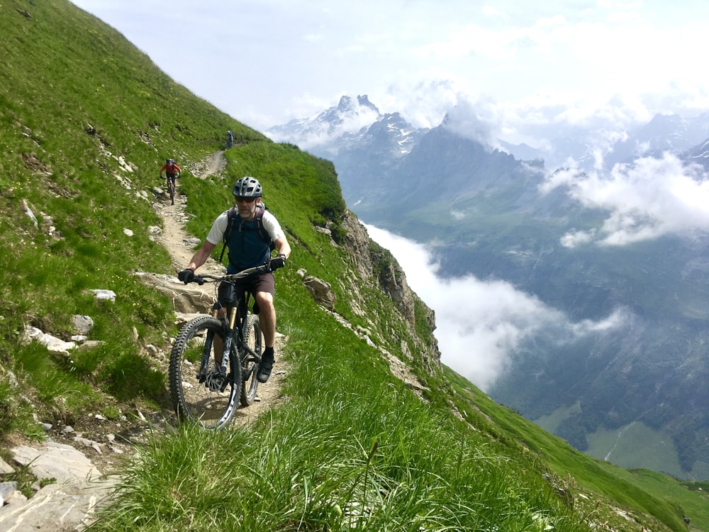 man in black jacket riding mountain bike on green grass field during daytime