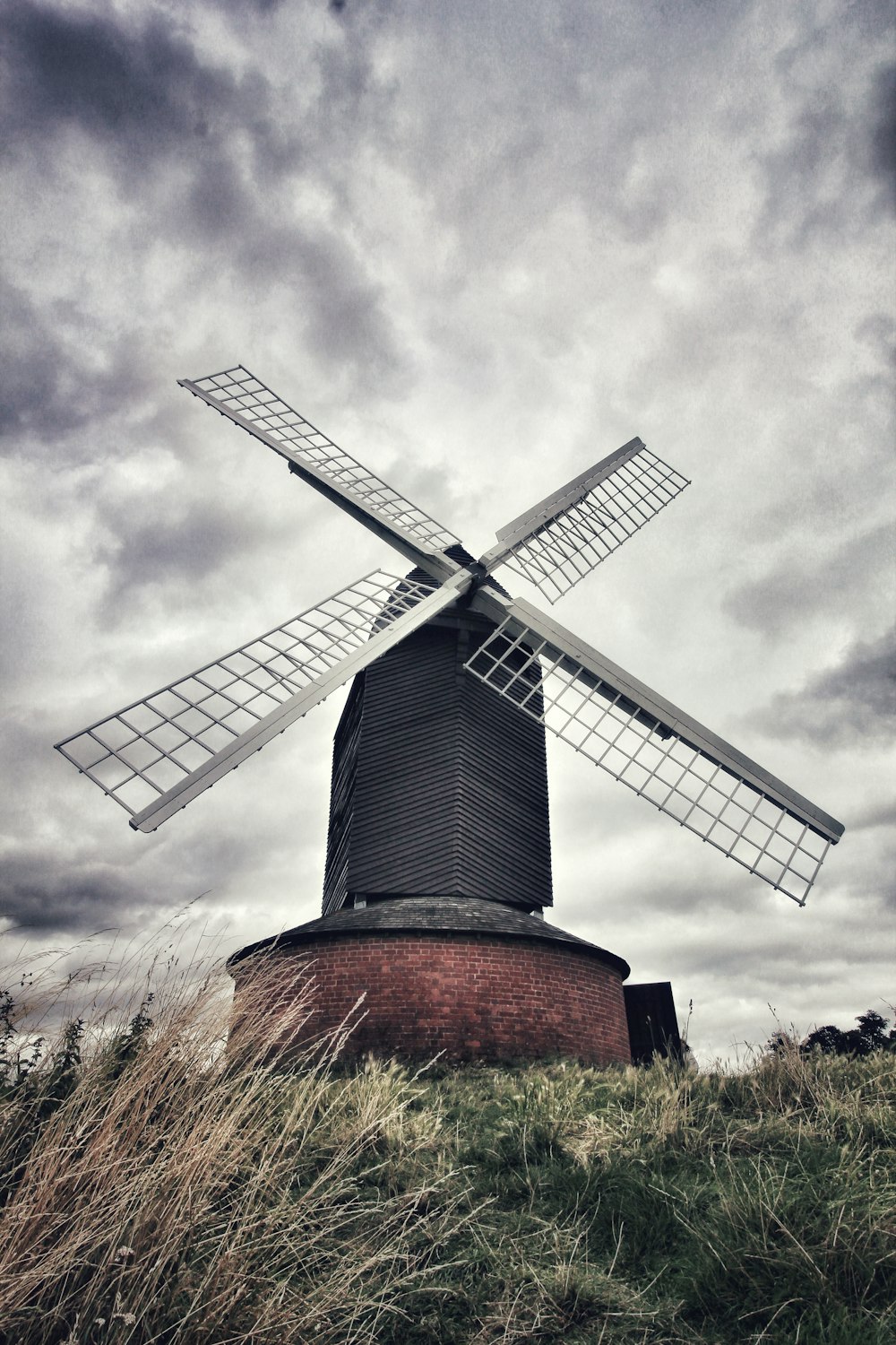 Molino de viento marrón y gris bajo el cielo nublado durante el día