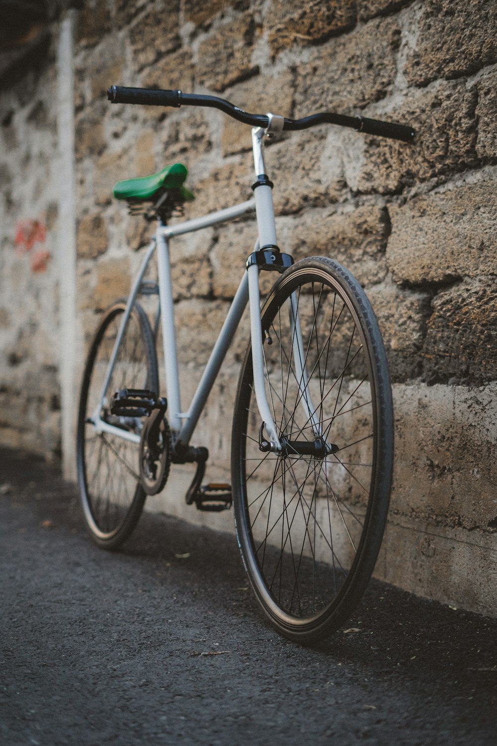 white city bike leaning on brown brick wall