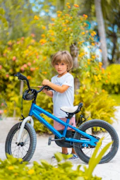 girl in white long sleeve shirt riding blue bicycle during daytime