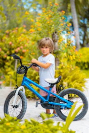 girl in white long sleeve shirt riding blue bicycle during daytime