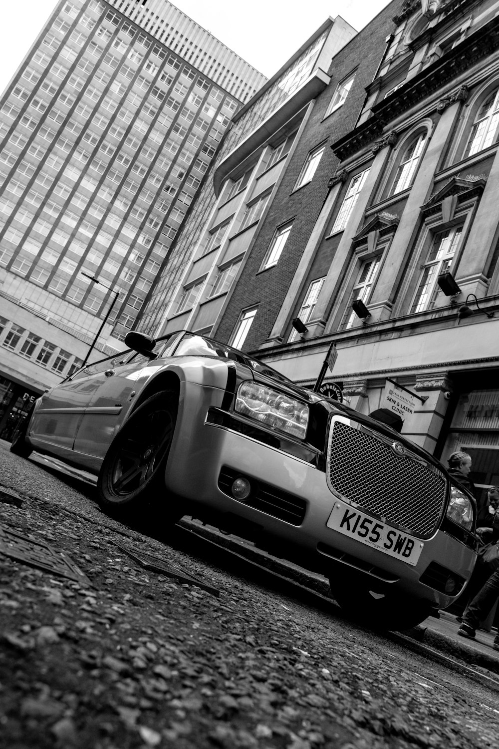 grayscale photo of mercedes benz coupe parked beside building