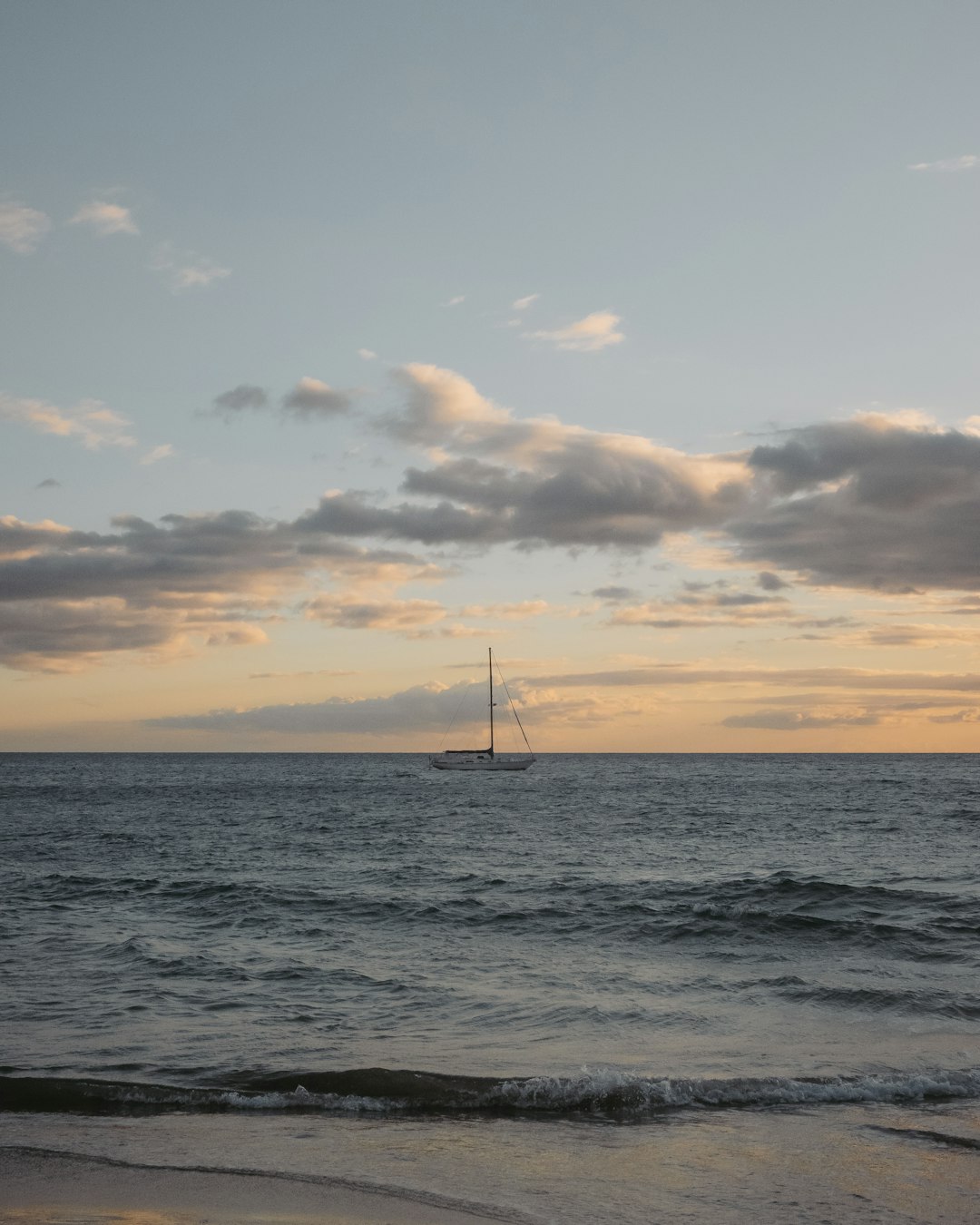 sailboat on sea under cloudy sky during sunset