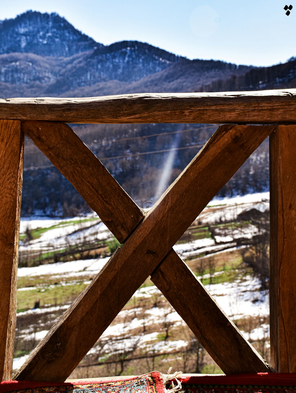 brown wooden fence near green trees and mountains during daytime