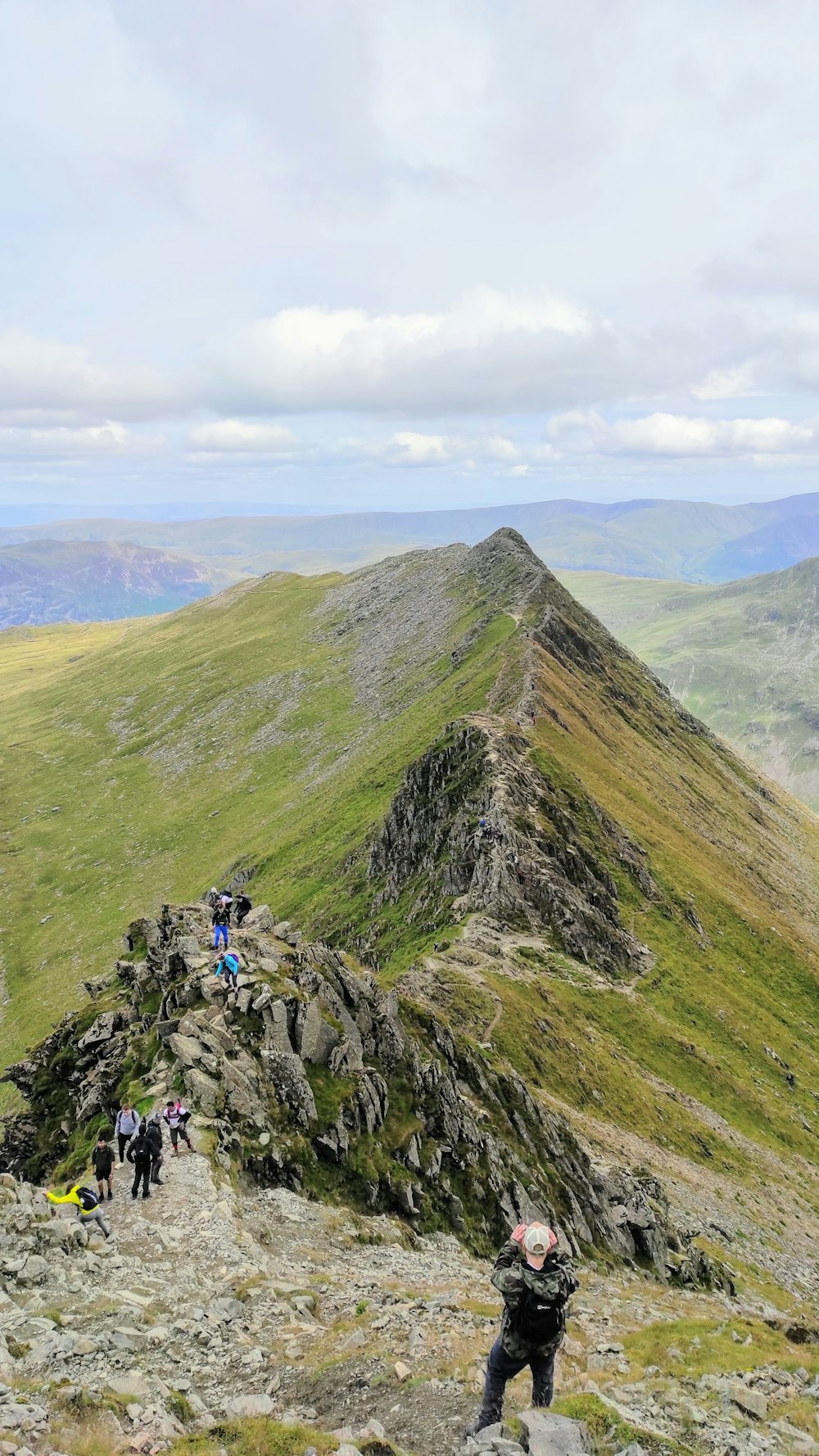 people hiking on green mountain during daytime