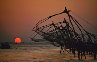 brown and white sail boat on sea shore during sunset