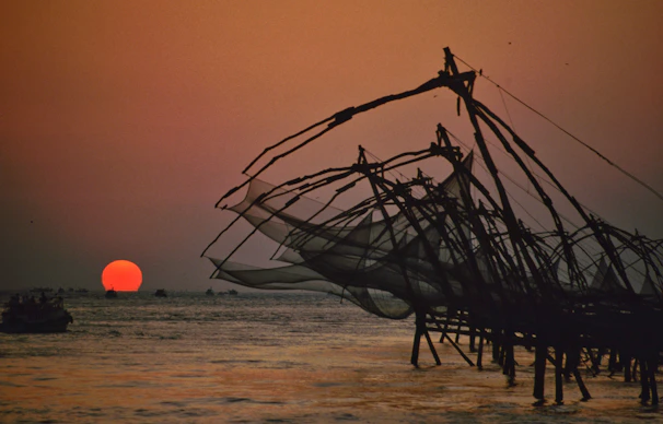 brown and white sail boat on sea shore during sunset