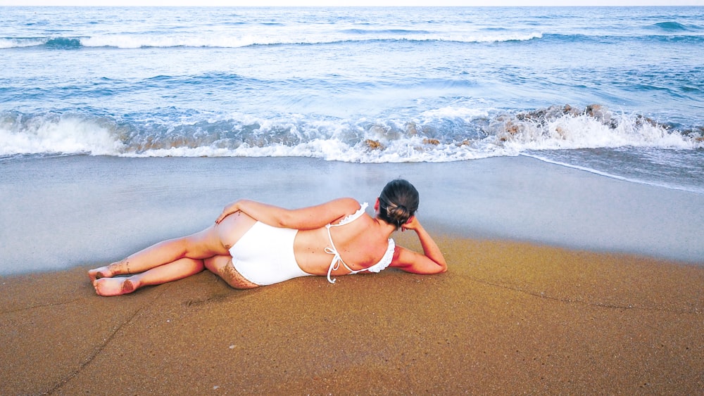 woman in white bikini lying on beach
