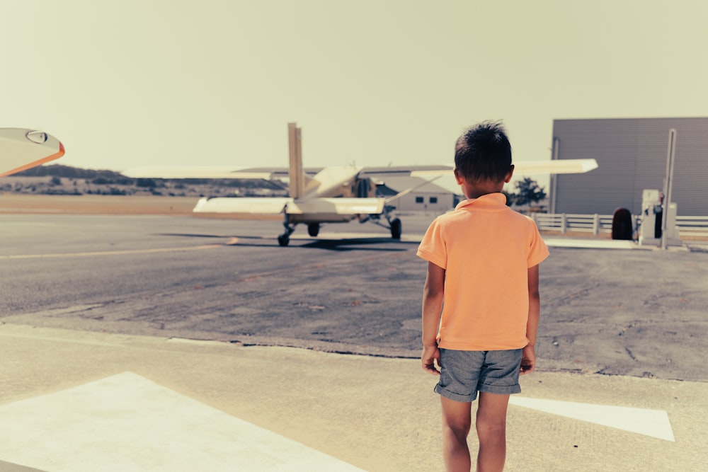 man in orange crew neck t-shirt standing on gray concrete floor during daytime