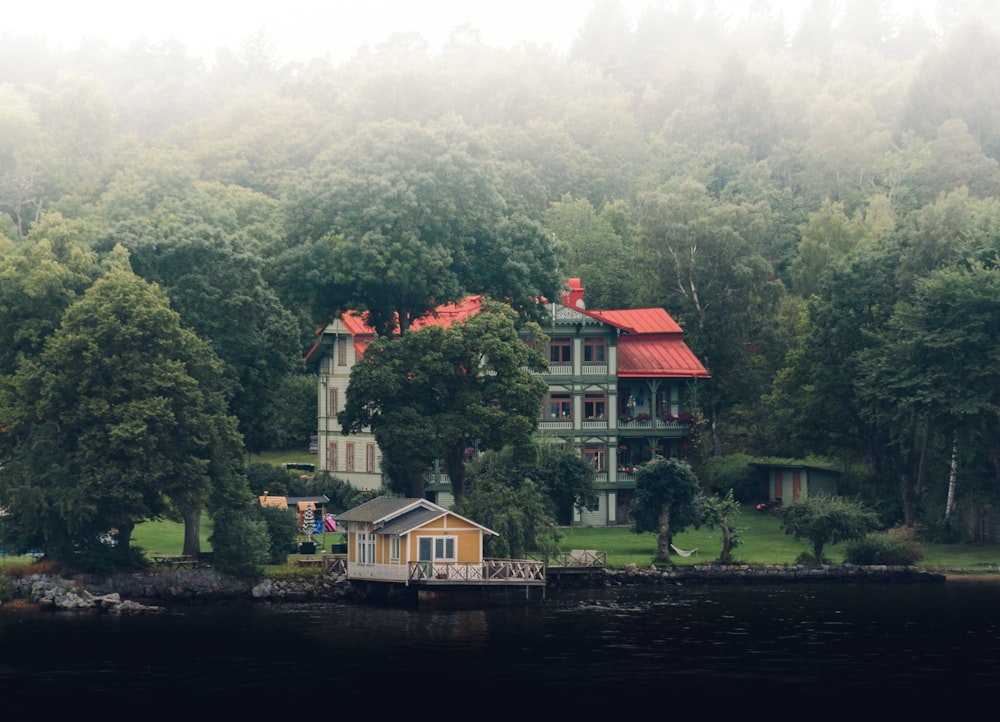 Casa bianca e marrone vicino agli alberi verdi e allo specchio d'acqua durante il giorno